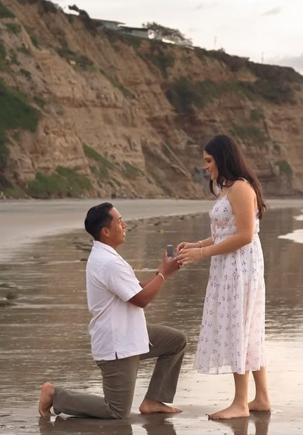 Beach proposal - a man kneeling to ask his partner to marry him