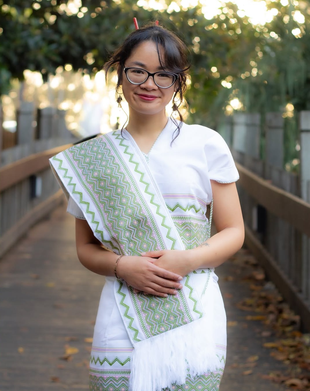 Woman smiling in a green and white sash with hands on her belly
